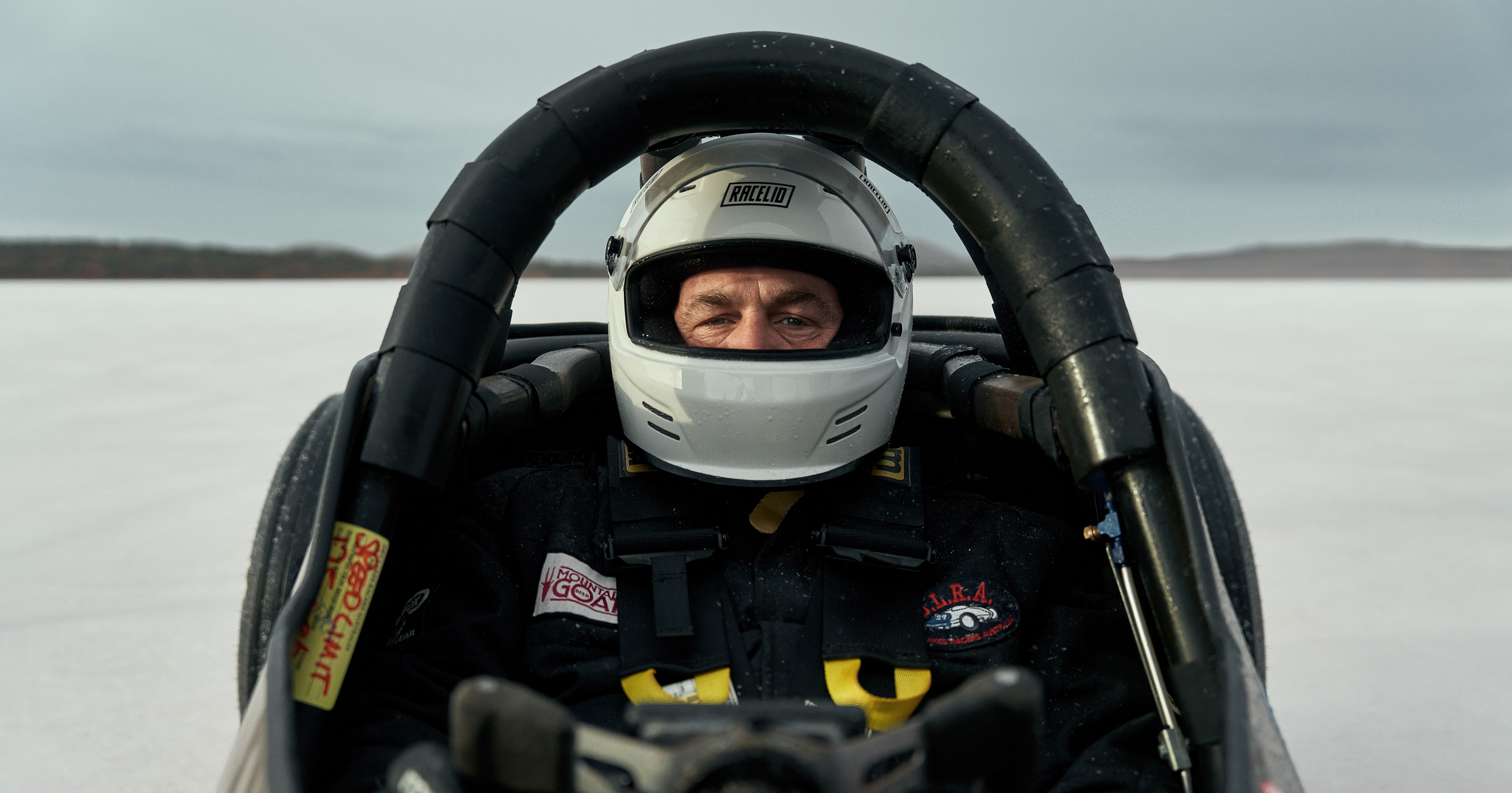 A man wearing a helmet sitting inside a racecar